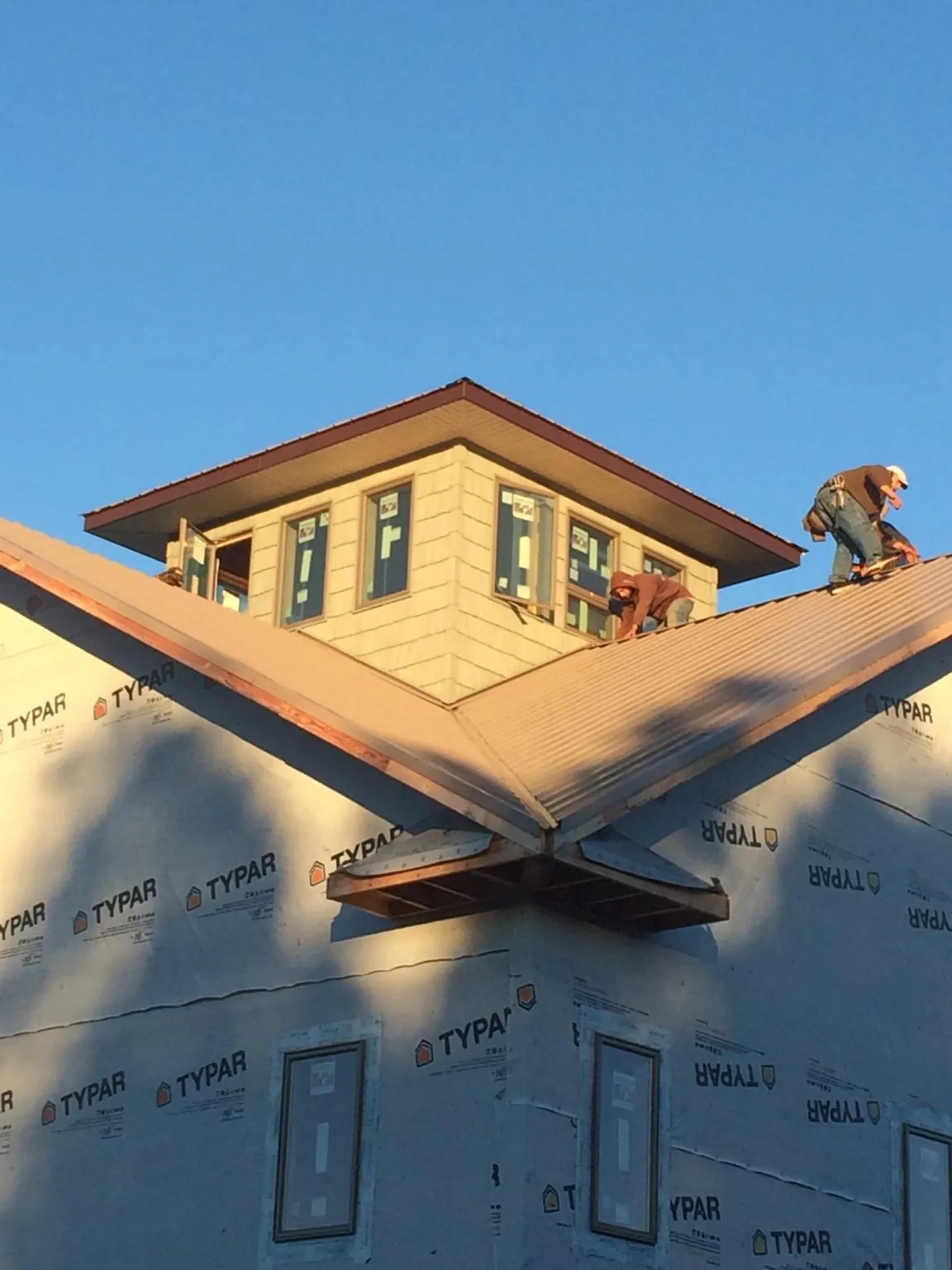 Roofers working around a rooftop cupola on a new metal roof at sunset — Roof Waterproofing in Wellington by Roofing Brothers